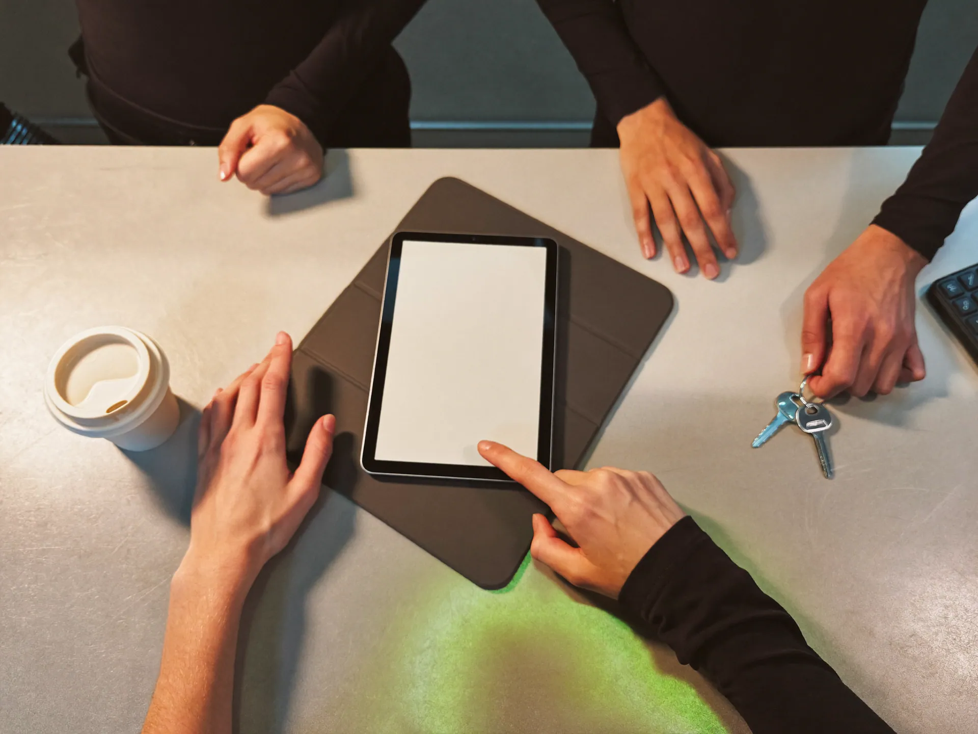 Mani dello staff di un centro fitness attorno a un tablet sul bancone della reception